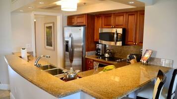 A kitchen with granite countertops, stainless steel appliances, wooden cabinets, and a built-in microwave.