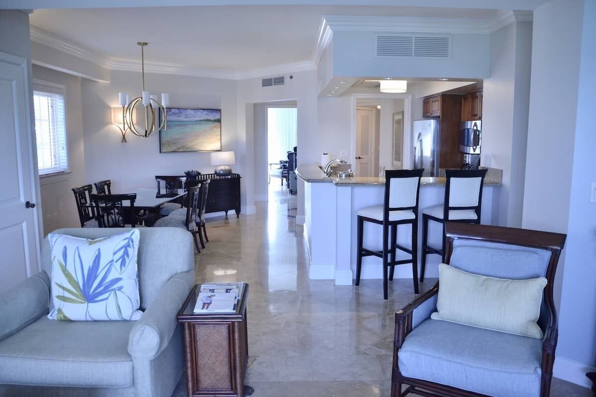 A spacious living room with a dining area, a kitchen, and a view of the dining area.