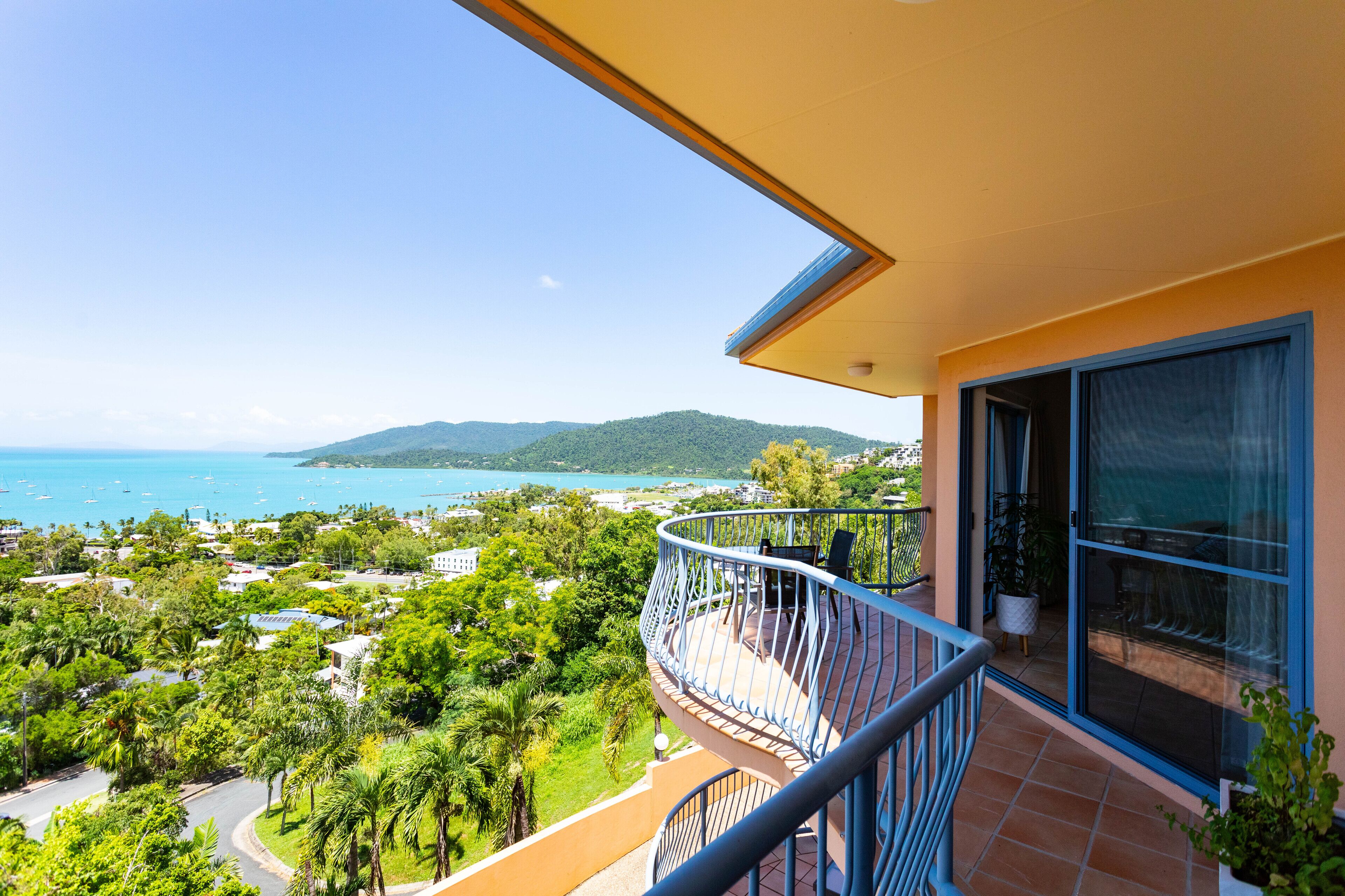 A balcony with a view of the sea and greenery.