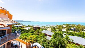 A residential area with a view of the sea, featuring houses with balconies and a clear sky. - 9 Starview Apartments (Airlie Beach)