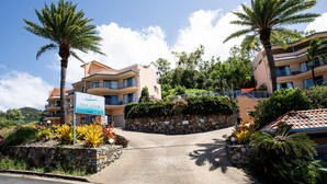 A multi-story hotel with a stone facade, balconies, and tropical landscaping. - 9 Starview Apartments (Airlie Beach)