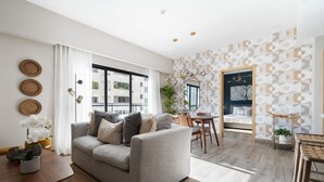 En moderne stue med en grå sofa, et træbord og et spiseområde med et lille bord og stole.