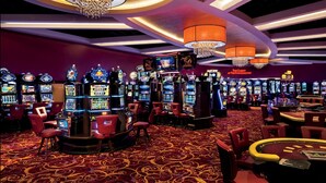 Un casino doté de nombreux jeux de machines à sous, de chaises de jeu rouges et d’une table de roulette.
