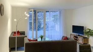 Una sala moderna con un sofá, un televisor y una lámpara de pie.