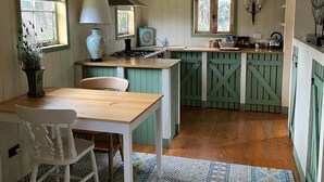 A kitchen with wooden cabinets, a stove, a sink, and a dining area with a table and chairs.