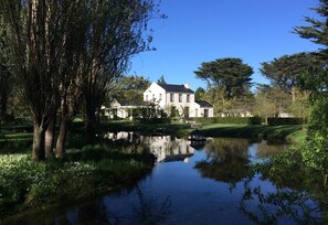 A large white house with a pond in front, surrounded by trees and greenery. - Rustic self contained cottage set in the beautiful grounds of Grayton House. (Woodend)