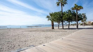 A beach with a wooden boardwalk, palm trees, and a clear sky. - Le Cormoran by Interhome (Saint Laurent du Var)