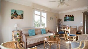 A cozy living room with a sofa, chairs, a table, and a ceiling fan. - Le Cormoran by Interhome (Saint Laurent du Var)