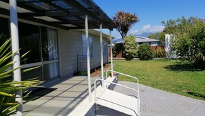 Ett bostadshus med en inglasad veranda, en liten trädgård och en klarblå himmel.