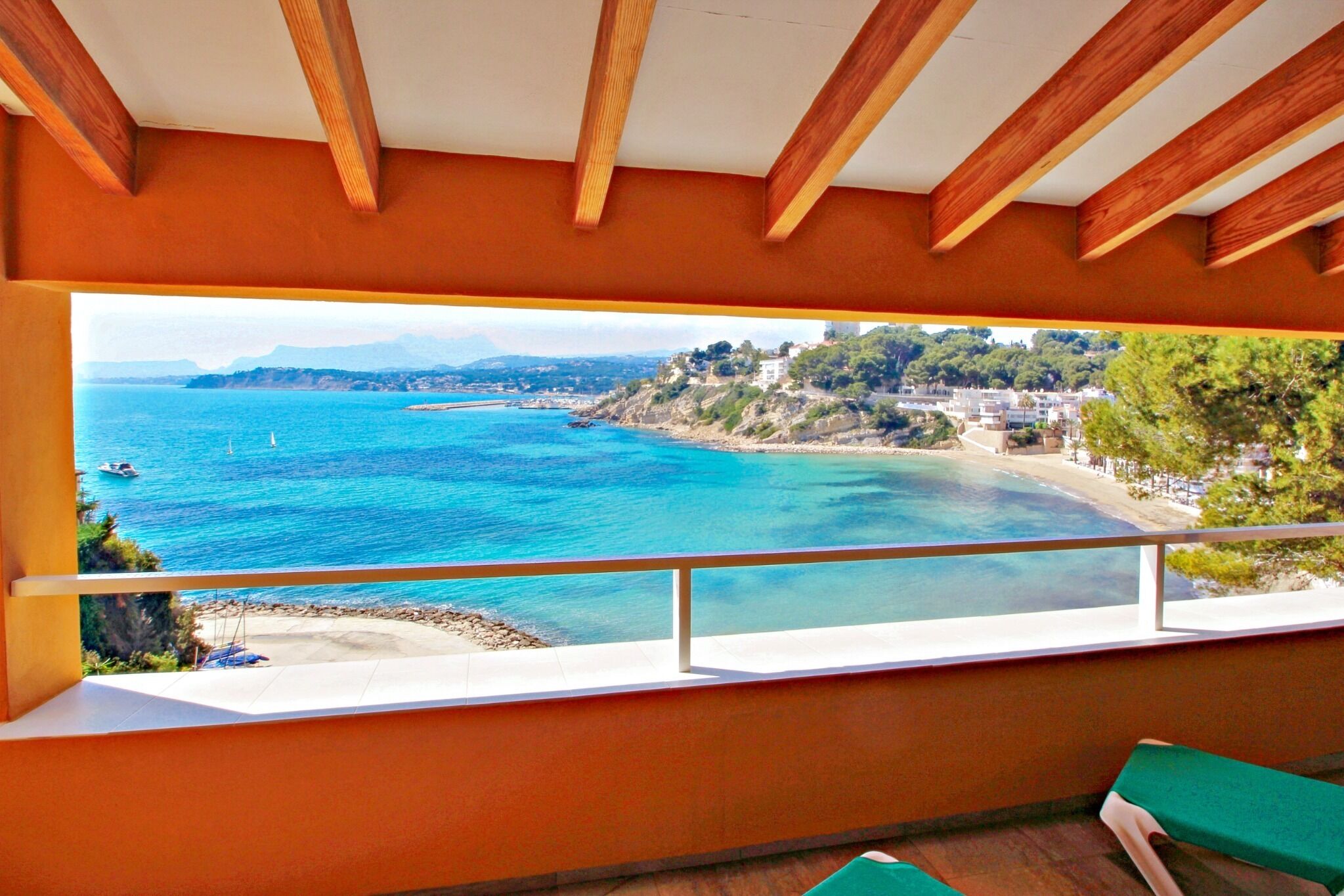 Uma varanda com vista para a área costeira, incluindo uma praia e uma cidade ao longe.