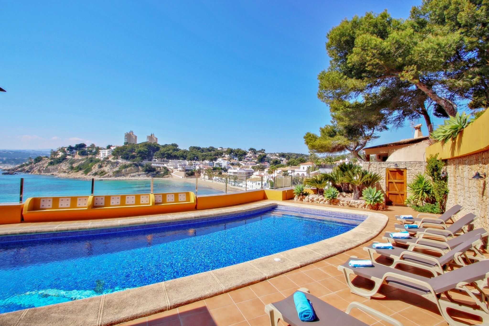 Une piscine avec vue sur la mer et une colline parsemée de bâtiments.
