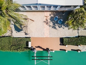 An aerial view of a resort with a pool, lounge chairs, and palm trees.