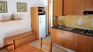 Een kleine keuken met houten kastjes, een ingebouwde magnetron en een spoelbak.