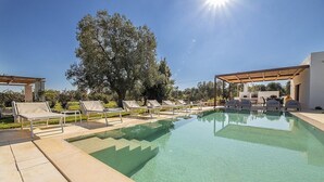 Une piscine aux eaux cristallines, dotée de chaises longues et d’une structure en forme de pergola.
