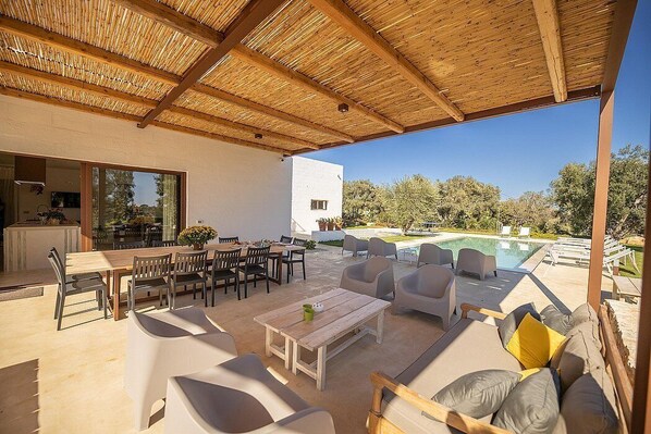 Eine Außenpatio mit Holzboden, einem Pool und einem Essbereich mit Tischen und Stühlen.