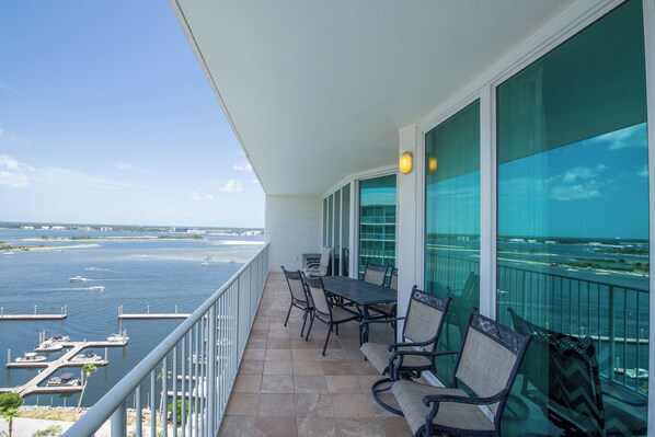 A balcony with a view of the water, a table, and chairs.