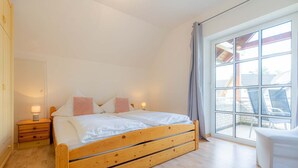 Une chambre à coucher avec un lit en bois, des tables de chevet et une grande fenêtre avec des rideaux.