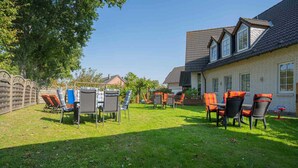 A courtyard with outdoor seating and a building with a tiled roof. - House Zur Sonnenseite - Apartment 3 Irmi (ID 415) (Garding, Kirchspiel)