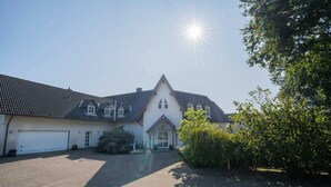 A large, single-story building with a steeply pitched roof and a central entrance. - House Zur Sonnenseite - Apartment 3 Irmi (ID 415) (Garding, Kirchspiel)