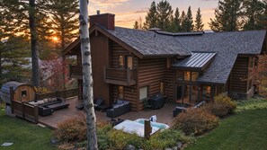 A log cabin with a deck, outdoor seating, and a hot tub.