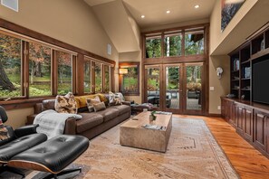 A spacious living room with a large window, a leather sofa, a coffee table, and a television.