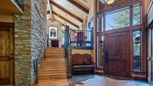 A wooden staircase leading to a second floor with a stone wall, a bench, and a large wooden door. - RMR: Sundance Ski Lodge | Luxury Ski - In / Ski - Out (Teton Village)