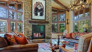 A cozy living room with a stone fireplace, leather sofas, and a large bear painting. - RMR: Sundance Ski Lodge | Luxury Ski - In / Ski - Out (Teton Village)
