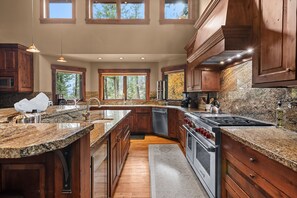A spacious kitchen with granite countertops, wooden cabinets, a built-in oven, and a large island with a sink.