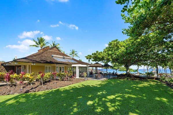 A house with a sloped roof, a covered patio with outdoor furniture, and a view of the ocean.