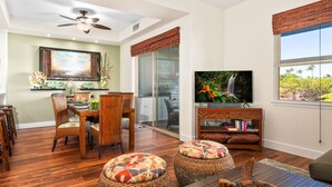 A spacious living room with a dining area, a large TV, and a view of the outdoors.