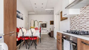 Una cocina moderna con estufa, horno y armarios de madera. Hay un comedor con mesa y sillas.