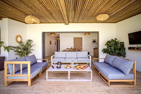 Un salon moderne avec deux canapés, une table basse et un coin repas visible à travers une porte ouverte.