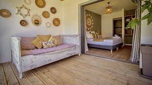 Ein gemütliches Zimmer mit einem weißen Sofa, einem Bett mit gemustertem Kopfteil und einer Holzbalkendecke.