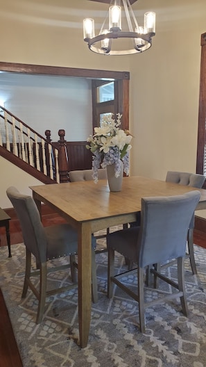 Un comedor con una mesa de madera, seis sillas y un jarrón de flores.