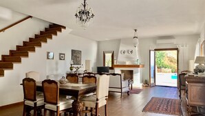 Ein geräumiges Wohnzimmer mit einer Holztreppe, einem Essbereich mit Holztisch und -stühlen sowie einem Kamin.