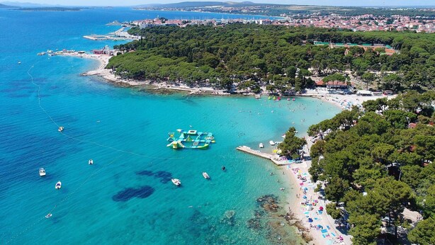 Ein Luftbild einer Küstenstadt mit Strand, Booten und einer schwimmenden Plattform.