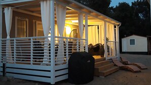 Ein kleines, weißes Gebäude mit einem Stockwerk, mit Veranda und überdachter Außenbereich.