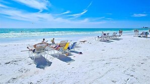 Een strand met meerdere ligbedden en mensen die ontspannen.