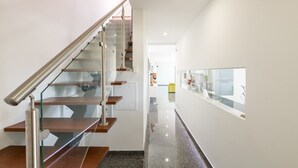 Un interno moderno con una scala in vetro, un pavimento lucido e una zona cucina visibile in lontananza.