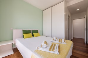 A hotel room with a bed, pillows, a bench, and towels.