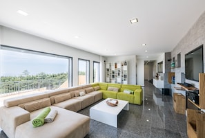 A modern living room with a sectional sofa, a coffee table, and a kitchen area with built-in appliances.