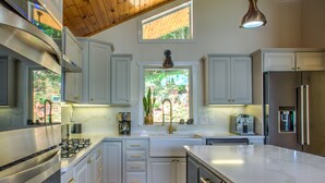 Cozinha moderna com armários brancos, eletrodomésticos de aço inoxidável e uma ilha grande.