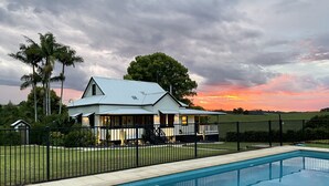 A house with a pool, surrounded by a fence and palm trees. - Benny’s Cottage  Luxury hinterland accomodation & photo shoot location (Clunes)