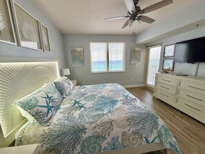 Ein Schlafzimmer mit einem Bett, einem Deckenventilator, einem Schminktisch und einem Fernseher.