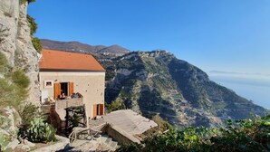 Un bâtiment en pierre avec un toit recouvert de tuiles rouges, un balcon et une vue sur un paysage montagneux.