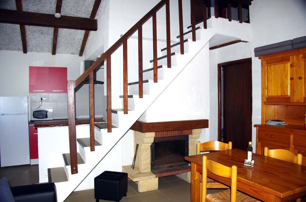 Eine Treppe führt zu einer zweiten Etage, einer Küche mit Mikrowelle, einem Essbereich mit Tisch und Stühlen sowie einem Kamin.