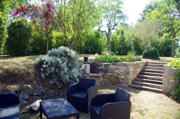 A patio area with wicker furniture, stone steps, and lush greenery.