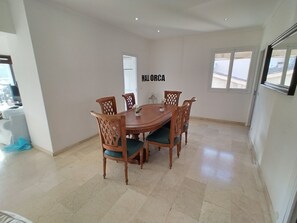 A dining area with a wooden table and chairs, a small potted plant, and a sign on the wall.