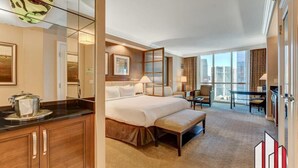 A hotel room with a large bed, a desk, a chair, a dining table, and a view of the city. - MGM Signature- Jacuzzi Lazy River StripView Studio (Las Vegas)
