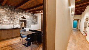 A modern kitchen with stone walls, wooden beams, and a dining area with a table and chairs. - La Cour Filaterie - A suite in the ❤️ of Annecy  🥐 breakfast included (Annecy)
